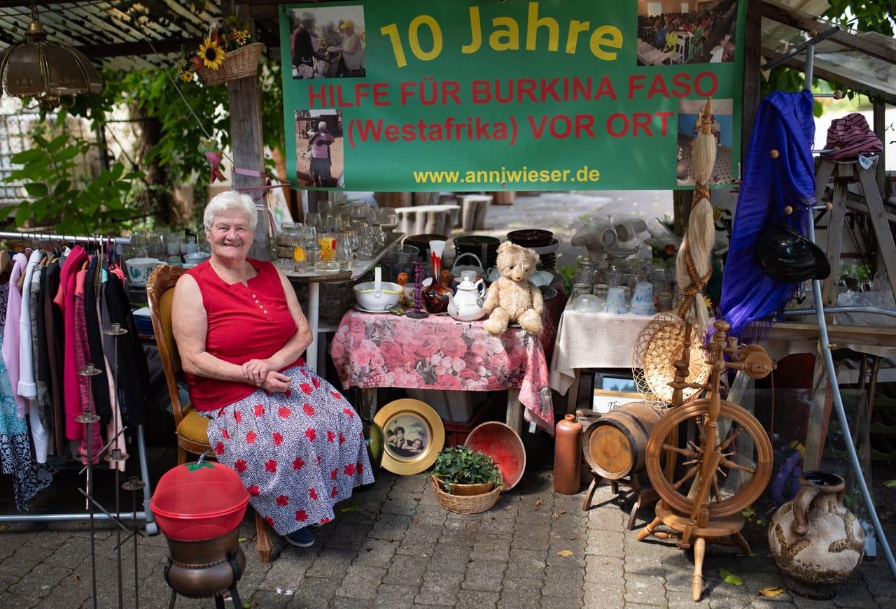 Anni am Verkaufsstand mit Banner '10 Jahre Hilfe für Burkina Faso'