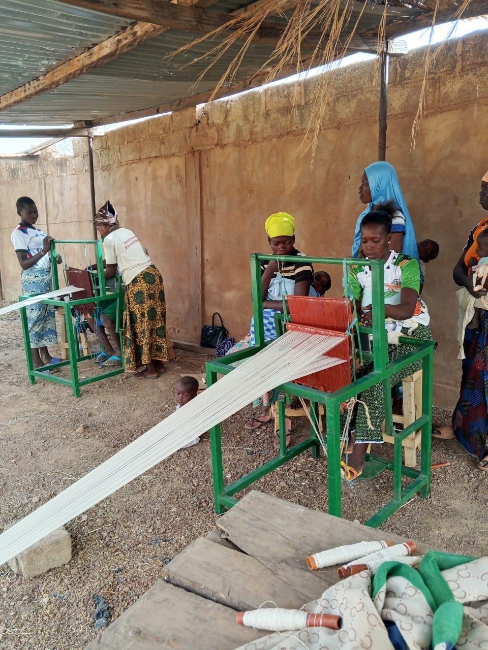 Frauen und Mädchen weben an Webstühlen in Burkina Faso